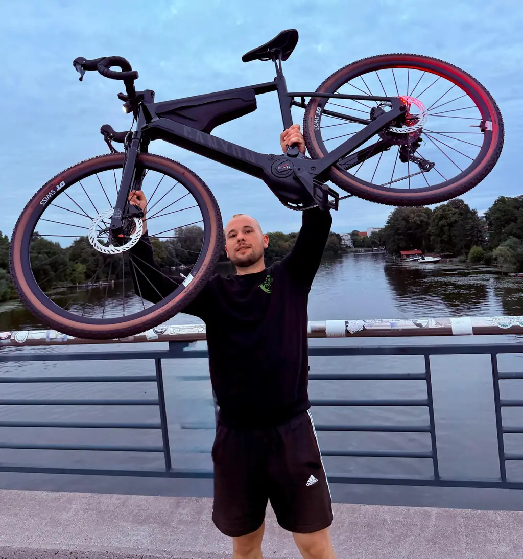 Paul Hübner, Geschäftsführer von Dein Radius, hält ein E-Bike über den Kopf