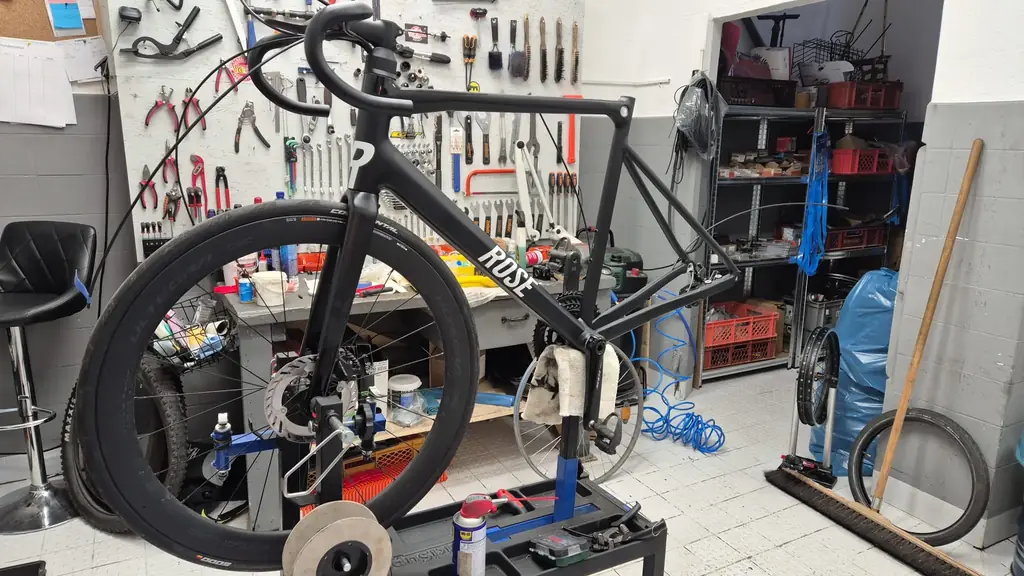 Schwarzes ROSE-Rennrad im Montageständer vor der Werkzeugwand der Werkstatt von Dein Radius